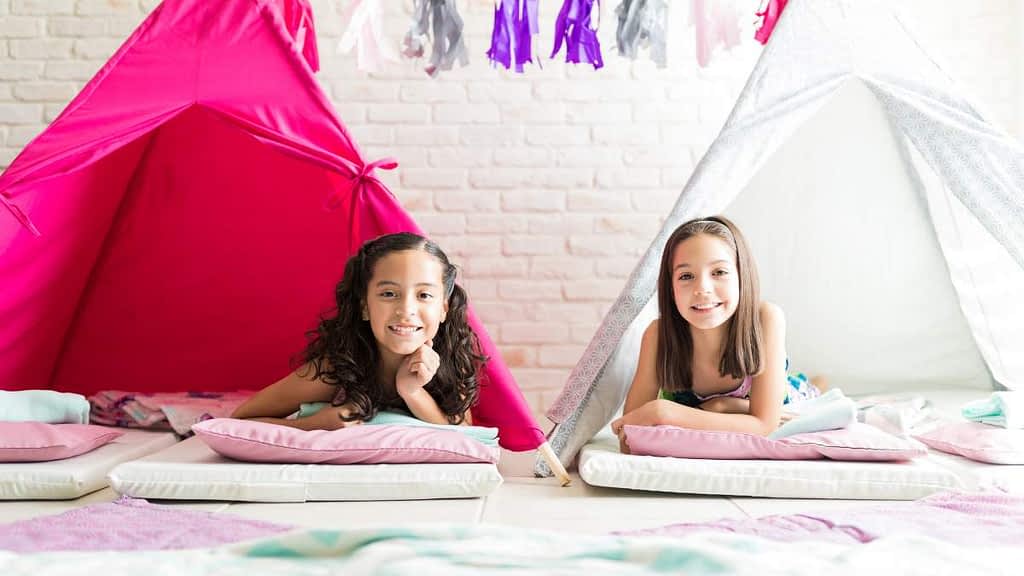 filles à une soirée pyjama dans des petites tentes de couleur girly