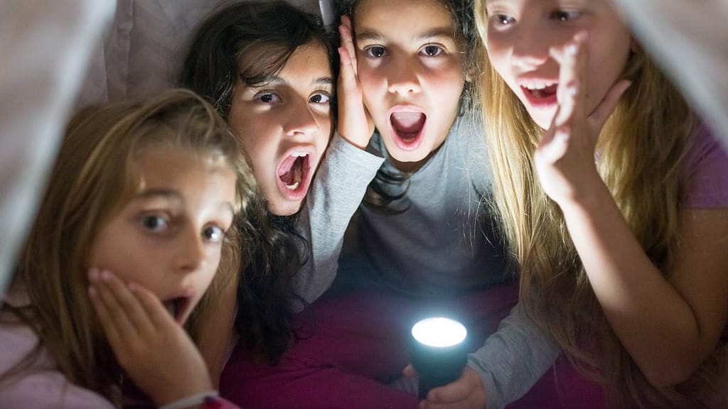 filles qui racontent une histoire effrayante avec une lampe torche.